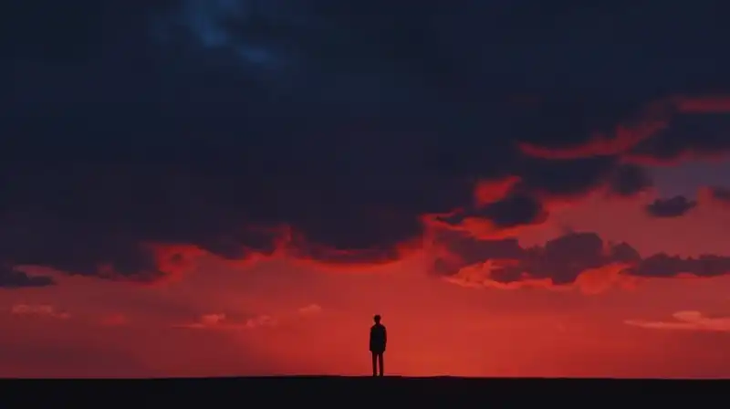 A lone figure stands beneath a dramatically colored, dual-tone sky