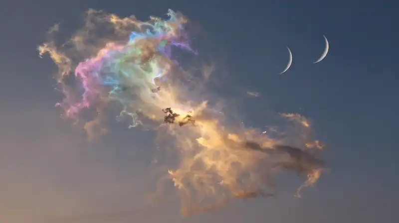 Iridescent nebula glows under twin crescent moons